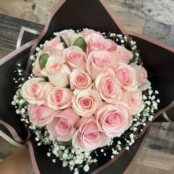 Bouquet of pale pink roses with baby's breath in black wrap
