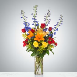 Tall bouquet of red and yellow roses with orange lilies in a glass vase