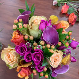 Bouquet of purple and peach roses with calla lilies and berry accents