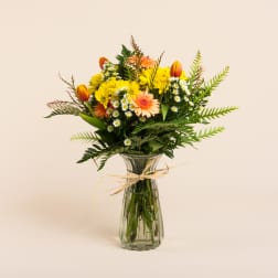 Mixed bouquet of yellow and peach flowers in a glass vase