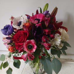 Mixed bouquet of red, pink, purple, and white flowers in a glass vase
