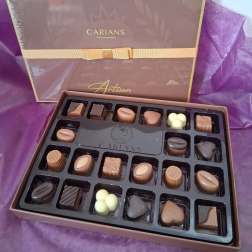 Box of assorted chocolates with a purple ribbon and tissue paper