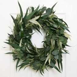Green foliage wreath with eucalyptus and long leaves on a white door