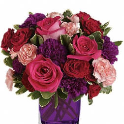 Bouquet of pink, red, and purple flowers in a purple glass vase