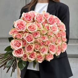 Large bouquet of pink roses held by a person in a black suit