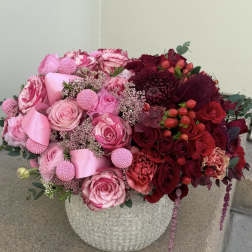 Pink and red rose arrangement in a textured stone vase