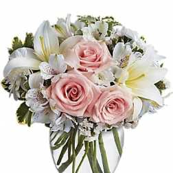 Pink roses and white lilies in a clear glass vase