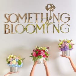 Three colorful floral arrangements held up against a wall with gold lettering