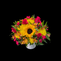 Bouquet of yellow sunflowers and pink flowers in a white vase