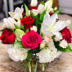Bouquet of red and white roses with white lilies in a glass vase