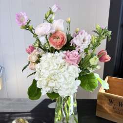 Mixed pink and white flowers arranged in a clear glass vase