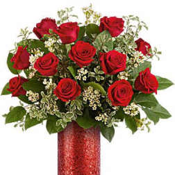 Red roses arranged in a red vase with white filler flowers