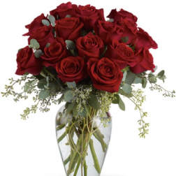 Red roses arranged in a clear glass vase with airy greenery