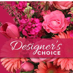 Pink floral arrangement with roses and daisies behind a Designer's Choice banner