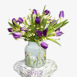 Purple tulips and white daisies in a painted vase with a butterfly decoration