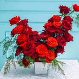 Red and orange roses in a clear square vase
