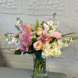 Pink and peach flowers arranged in a clear glass vase