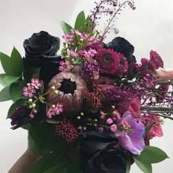 Bouquet of black roses and pink flowers with green leaves