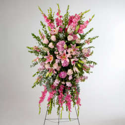 Tall standing spray of pink lilies, roses, and mixed blooms on an easel