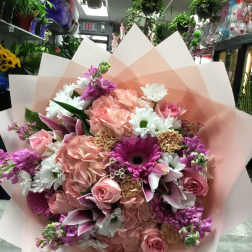 Large bouquet of pink and white flowers wrapped in pale pink paper