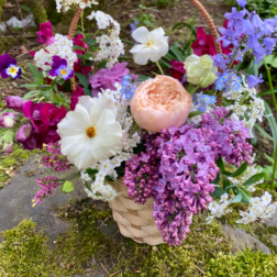 Basket of mixed pastel flowers with a woven handle