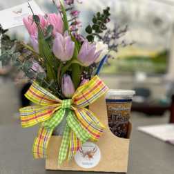 Gift caddy with pastel tulip bouquet, plaid bow, and iced tea cup on a table