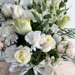 White roses and chrysanthemums in a glass vase with a ribbon