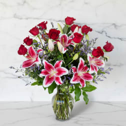 Red roses and pink lilies in a clear glass vase