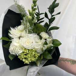 White bouquet with roses, hydrangeas, and chrysanthemums wrapped in black paper