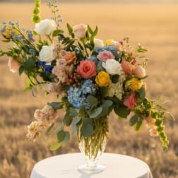 Mixed roses and blue flowers in a clear glass vase on a round table