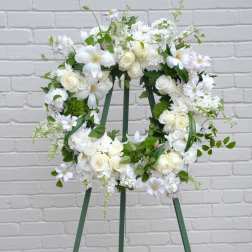 White floral wreath on a green easel stand