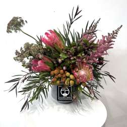 Pink protea arrangement in a gray container