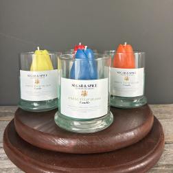 Set of glass jar candles with colorful tulip-shaped wax on a round wooden stand.