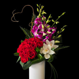 Red roses and purple orchids in a white vase