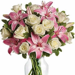 Pink lilies and white roses arranged in a clear glass vase