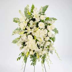 White floral standing spray with lilies, roses, and ferns