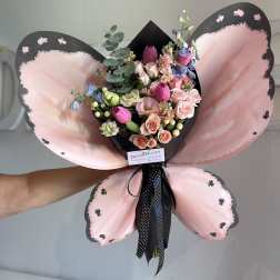 Pink and black butterfly-shaped bouquet with mixed flowers and ribbon