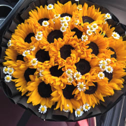 Bouquet of sunflowers with small white daisies in black wrap