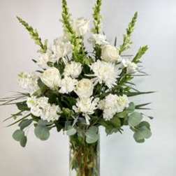 White floral arrangement in a clear glass vase with tall green spikes