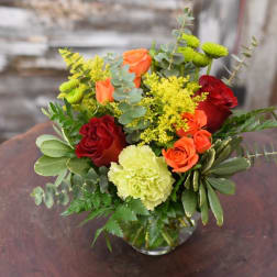 Bouquet of red and orange roses with yellow flowers in a glass vase