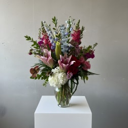 Tall mixed bouquet in a clear glass vase with pink lilies and white hydrangea