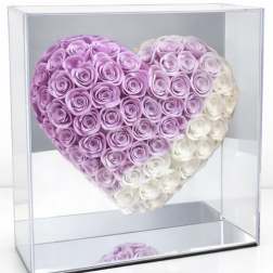Heart-shaped arrangement of pink and white roses in a clear display box