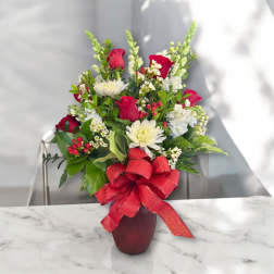 Red roses and white flowers in a vase with a red bow