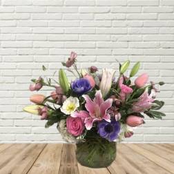 Mixed pink and purple flower arrangement in a glass vase