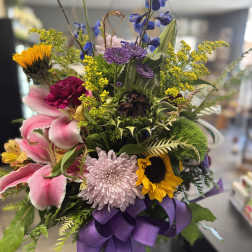 Mixed bouquet with lilies, sunflowers, chrysanthemums, and a purple ribbon