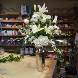 White lilies and roses arranged in a tall silver vase
