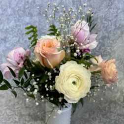 Pastel bouquet of roses and ranunculus in a white vase