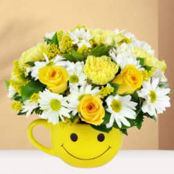 Yellow and white flower arrangement in a smiley-face mug