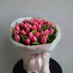 Bouquet of pink tulips wrapped in white paper with a satin ribbon