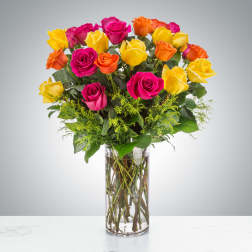 Bouquet of pink, yellow, and orange roses in a clear glass vase